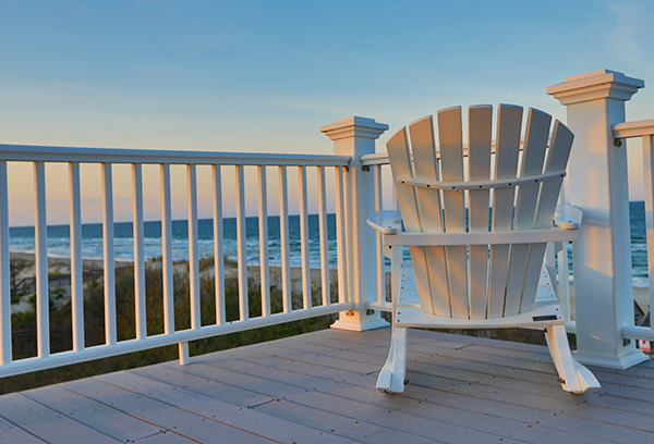 Empty Adirondack chair on a balcony deck overlooking the beach and the ocean in the Outer Banks of North Carolina